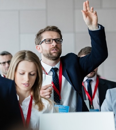 persona levantando para realizar una pregunta durante una conferencia